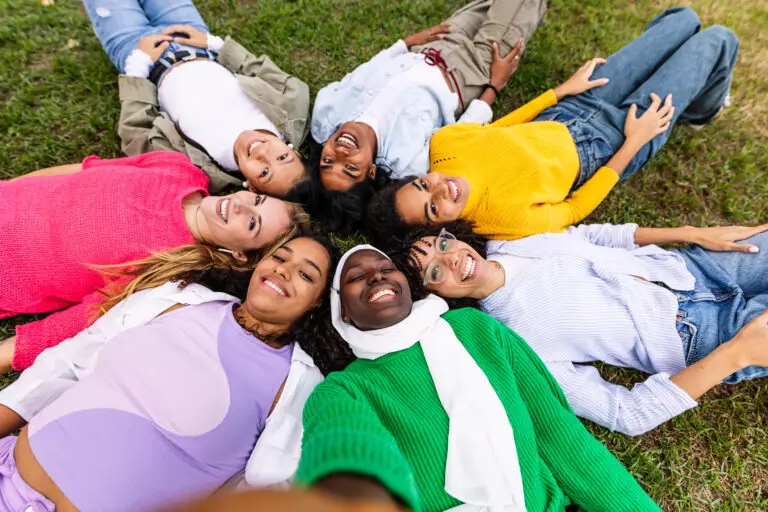 Happy group of women lying on circle on grass taking selfie portrait at park