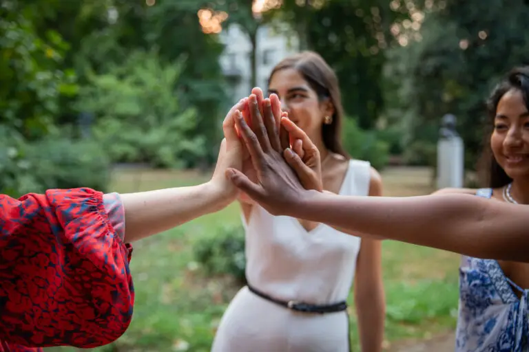 Multi ethnic group of female friends join hands together, international women's day concept